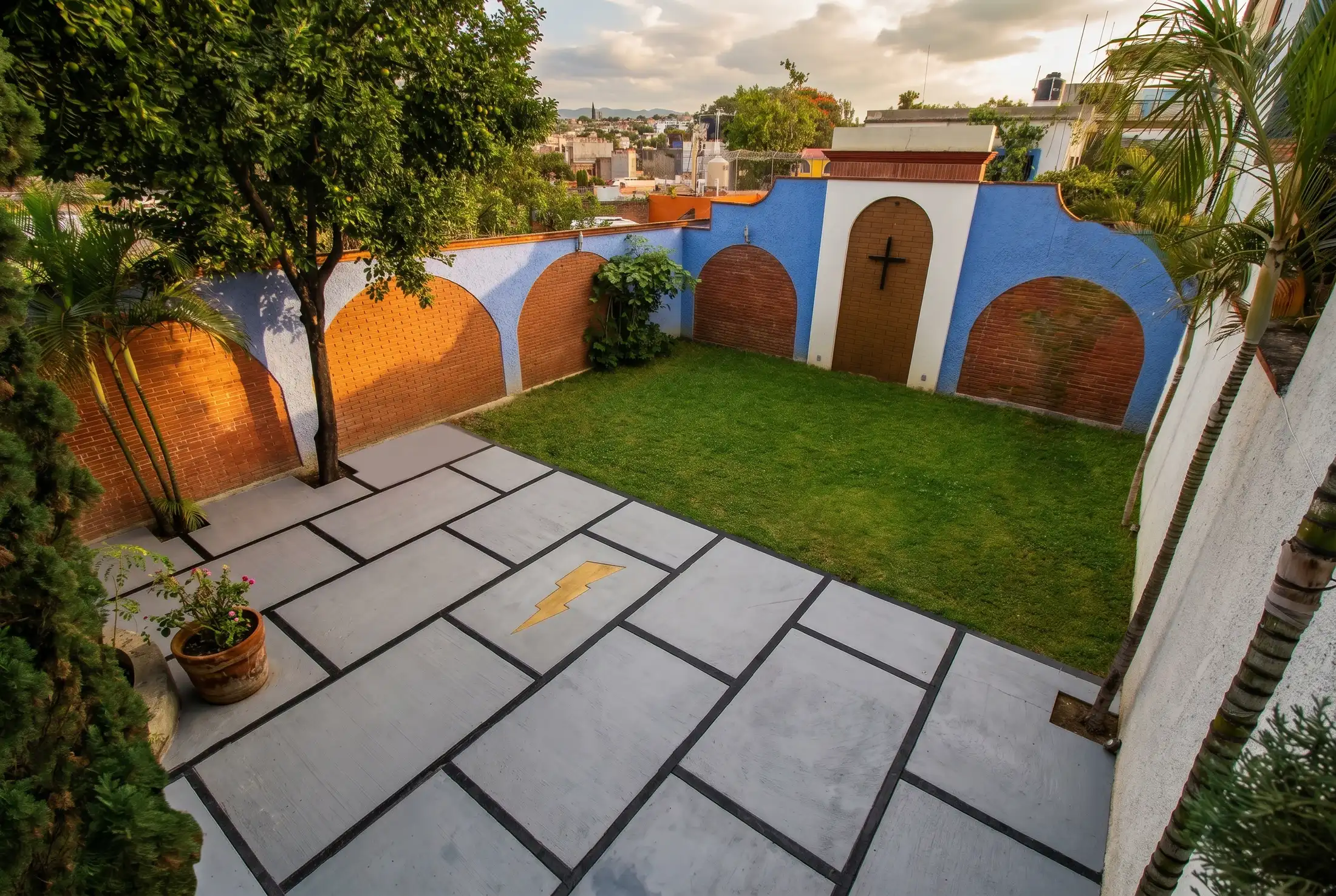 Patio de Rayito con jardín y muros azules con arcos de ladrillo