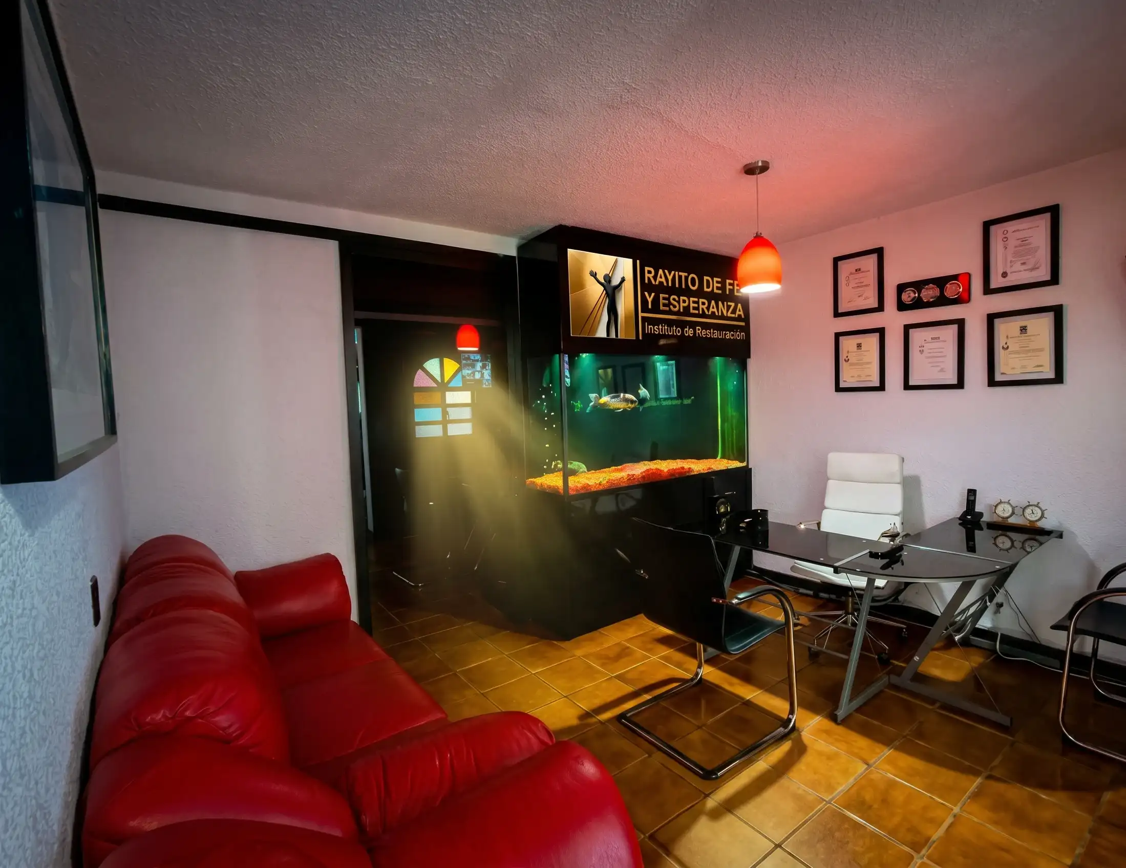 Recepción con sillón rojo, acuario y luz que entra por un vitral