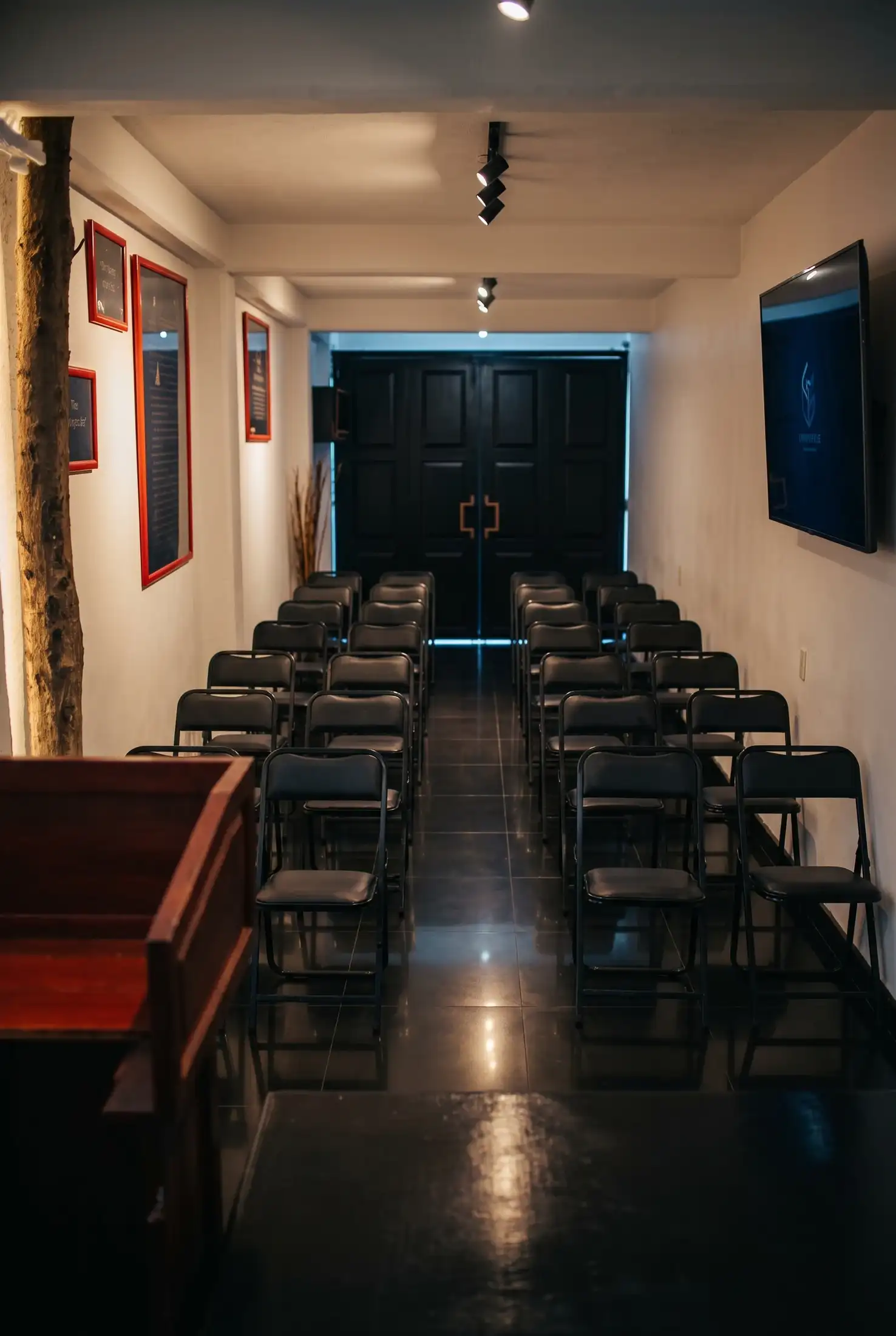 Sala de terapia grupal con sillas, pantalla y cuadros en las paredes
